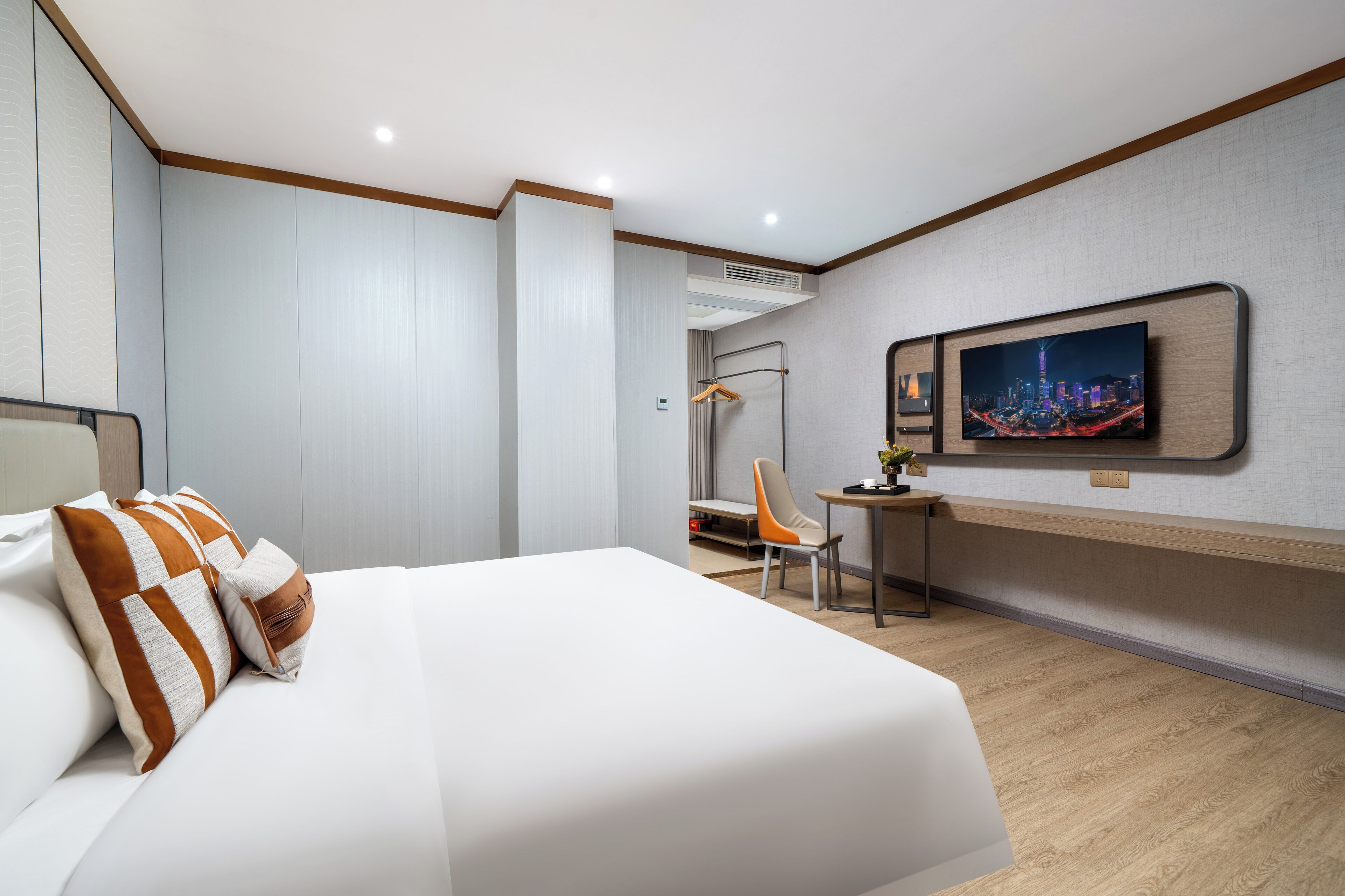 A modern hotel room with a large bed, a desk, and a television.