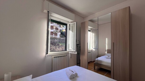 Une chambre d’hôtel avec un lit, une fenêtre, un radiateur, un miroir et une armoire.