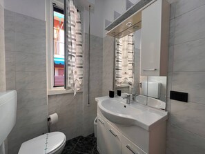 Un baño moderno con inodoro, lavamanos y zona de ducha.