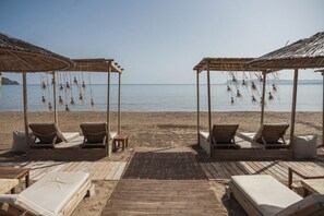 Ein Strand mit Holzpavillons, Liegestühlen und einer Holzterrasse.