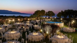 Un evento al aire libre con mesas y sillas redondas, una piscina y un paisaje pintoresco.