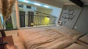 Een slaapkamer met een groot bed, een bureau en uitzicht op het balkon.