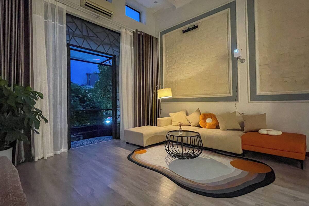 A modern living room with a sofa, a coffee table, and a view of the outdoors.