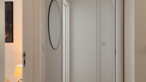Een hal met een houten vloer, witte muren en een deur aan het einde.