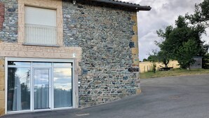 A stone building with a garage door, a large glass entrance, and a sign indicating a location. - GITE in the countryside, fully renovated, 30 mn from Lyon, near l'Arbresle (Savigny)