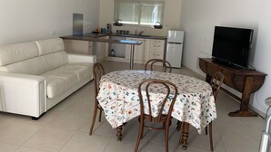 A compact living space with a kitchenette, a sofa, a dining table with chairs, and a TV. - GITE in the countryside, fully renovated, 30 mn from Lyon, near l'Arbresle (Savigny)