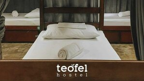 A single bed with a wooden headboard and a white mattress, flanked by curtains, in a hostel room. - Teofel Hostel by Hiverooms (Cebu City)