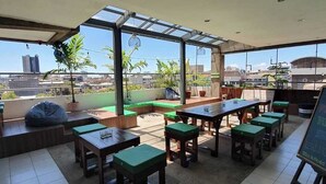 A rooftop patio with outdoor seating, a view of the cityscape, and a chalkboard menu. - Teofel Hostel by Hiverooms (Cebu City)