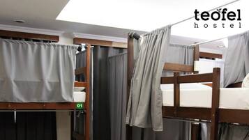 Habitación de albergue con literas, cortinas y un cartel con el número de la habitación.