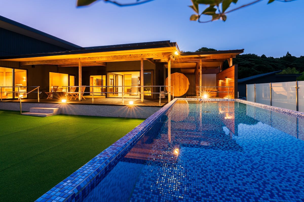 Un hôtel moderne doté d’une piscine, d’un espace extérieur aménagé et d’une entrée bien éclairée.
