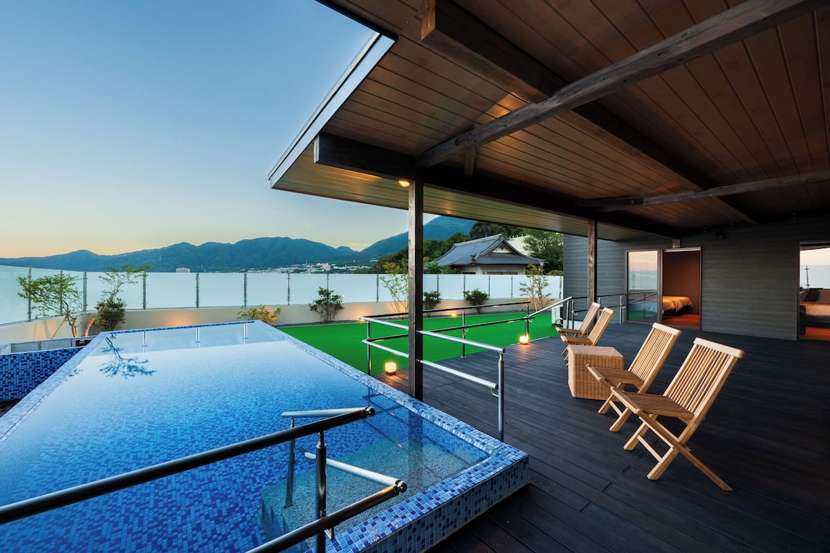 Une piscine à débordement située sur le toit, avec une terrasse en bois et une vue sur les montagnes.