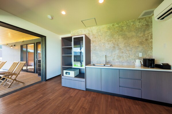 A modern kitchen with a built-in island, wooden flooring, and a view of the outdoors. - Umine Annex (Beppu)