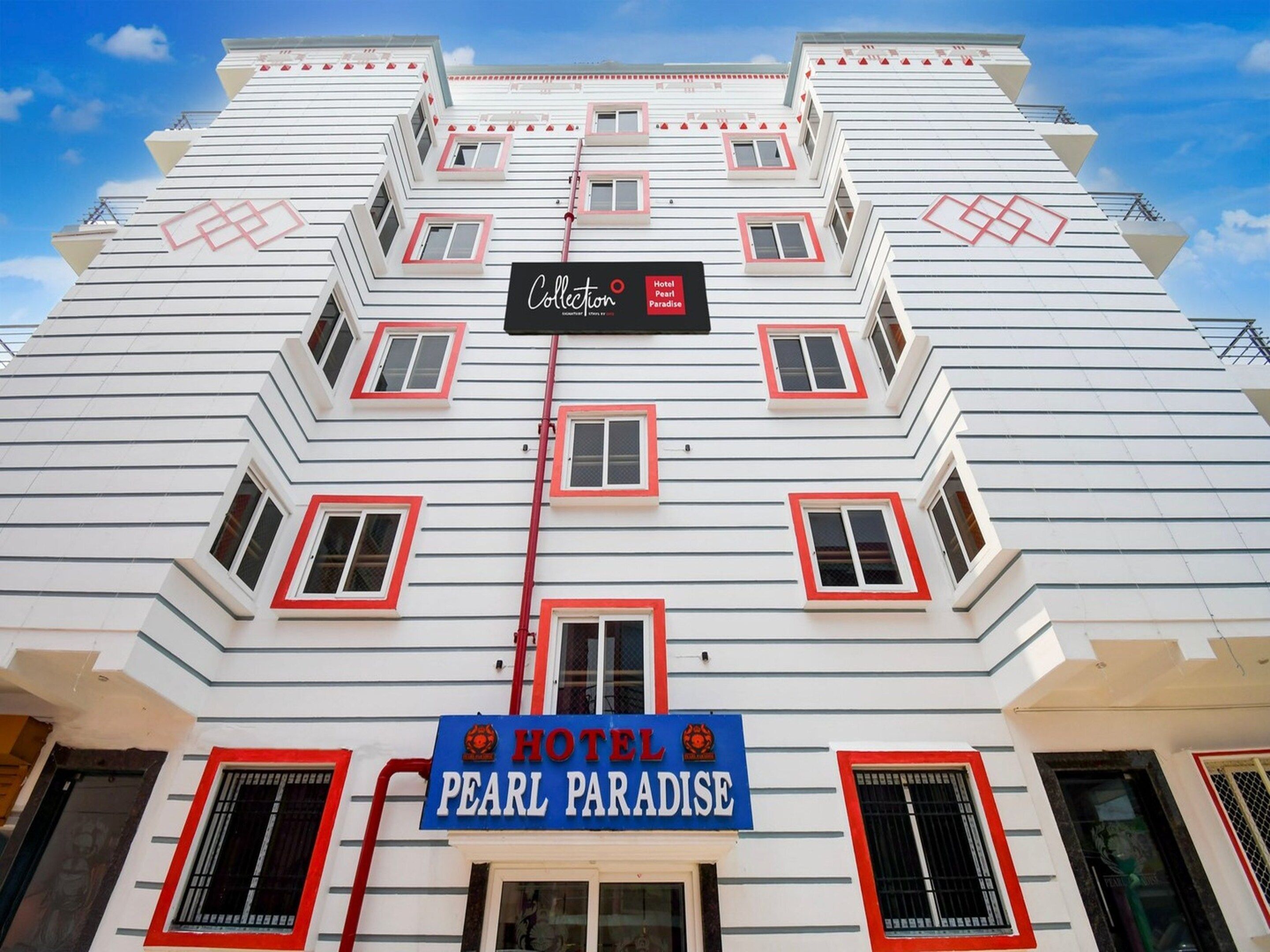 A multi-story hotel with a distinctive zigzag facade, multiple balconies, and a prominent sign for 'Hotel Pearl Paradise'.