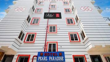 A multi-story hotel with a distinctive zigzag facade, multiple balconies, and a prominent sign for 'Hotel Pearl Paradise'.