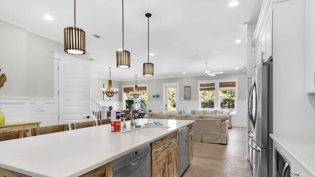 Una cocina moderna con una isla grande, armarios de madera, electrodomésticos de acero inoxidable e iluminación colgante.