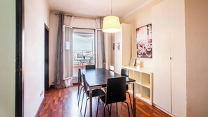 A dining area with a table and chairs, a hanging light fixture, and a view through a glass door. - A3IND1123- Ático near Sagrada Familia (Barcelona)