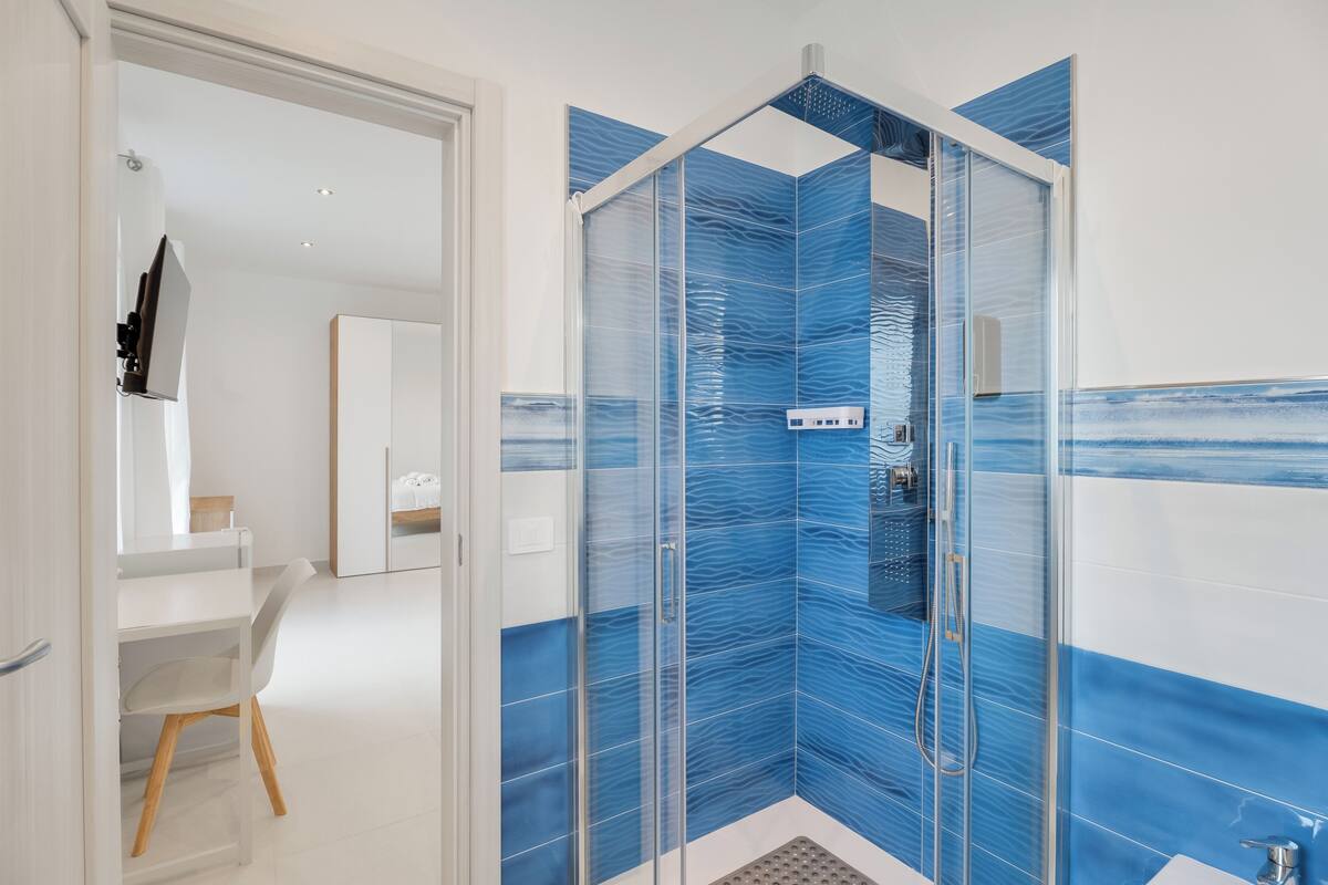 Une salle de bain moderne avec une douche à parois de verre, un lavabo blanc et un miroir.