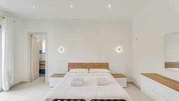 Un dormitorio moderno con una cama grande, mesitas de noche, un cabecero de madera y un espejo en la pared.
