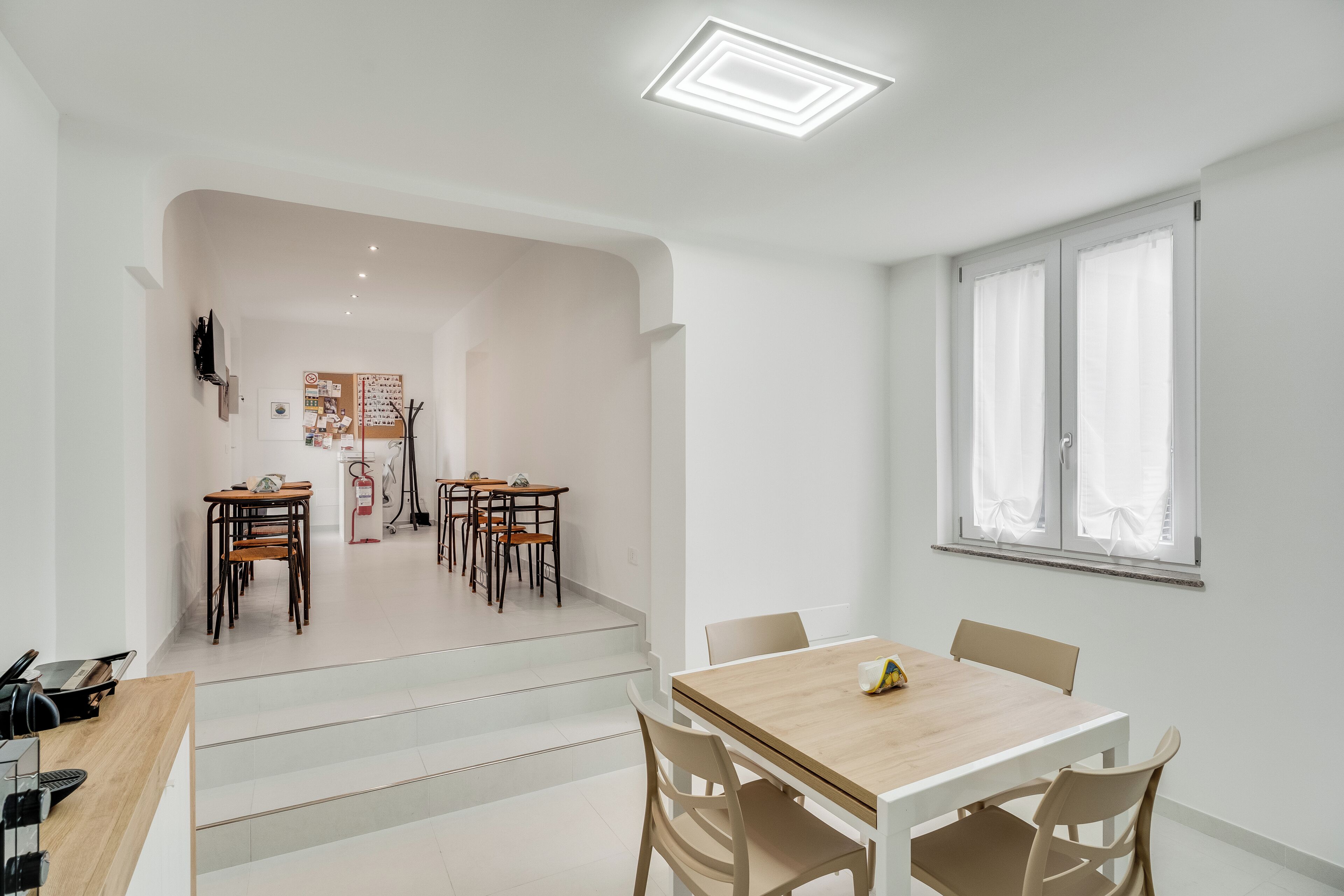 Un interior moderno con comedor, una escalera y un ventanal con cortinas.