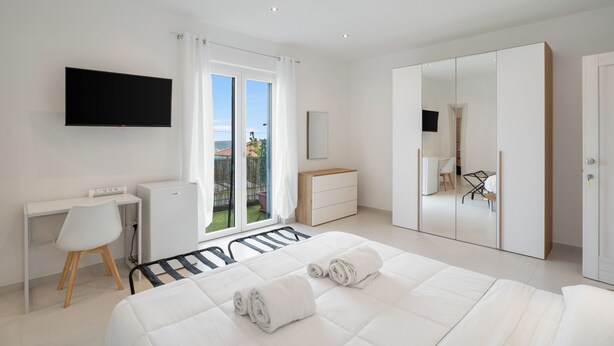 A modern bedroom with a bed, a desk, a TV, and a wardrobe. - B&B Santa Maria (Agerola)
