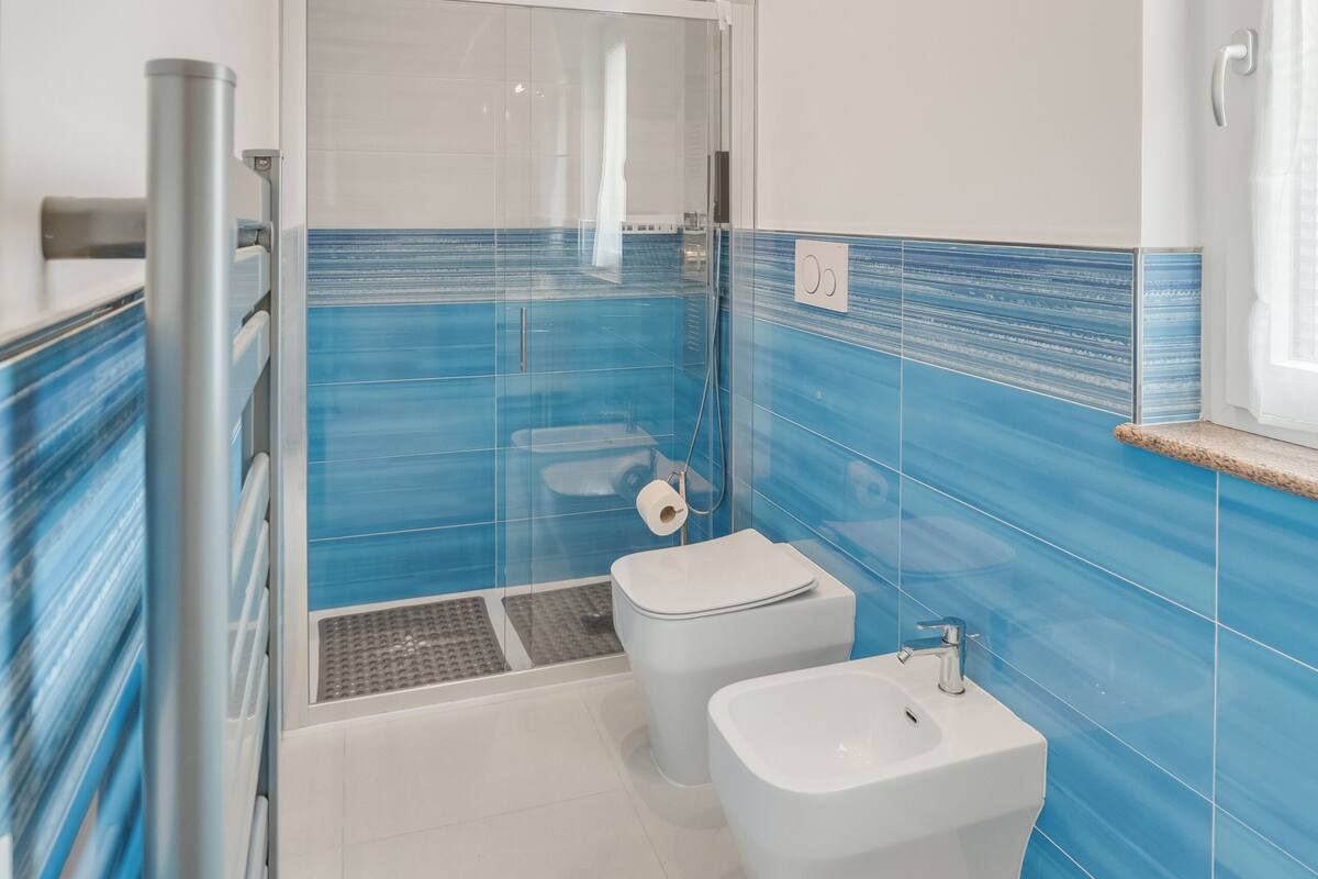 Une salle de bain avec une douche, deux lavabos et un espace douche séparé par des parois en verre.