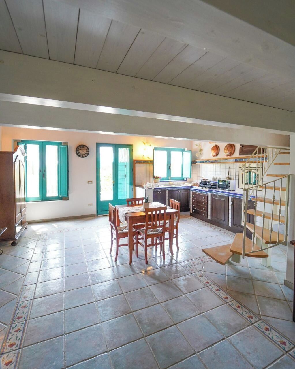 Una cocina amplia con comedor, armarios de madera y una escalera.