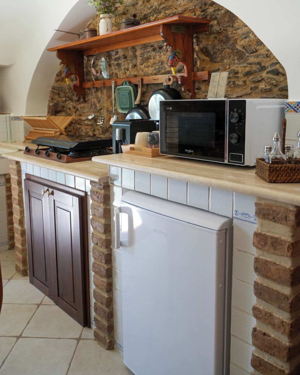 A kitchen with a stone wall, a microwave, a stove, and a refrigerator.