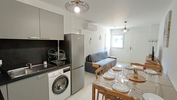 A compact kitchen with a washing machine, a refrigerator, and a dining area with a table set for four. - T2 with garden and parking, 6 ppl - Saint-Lary-Soulan (Saint-Lary-Soulan)