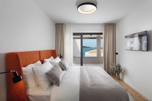 Una habitación de hotel moderna con una cama grande, un televisor de pantalla plana y vista al mar.