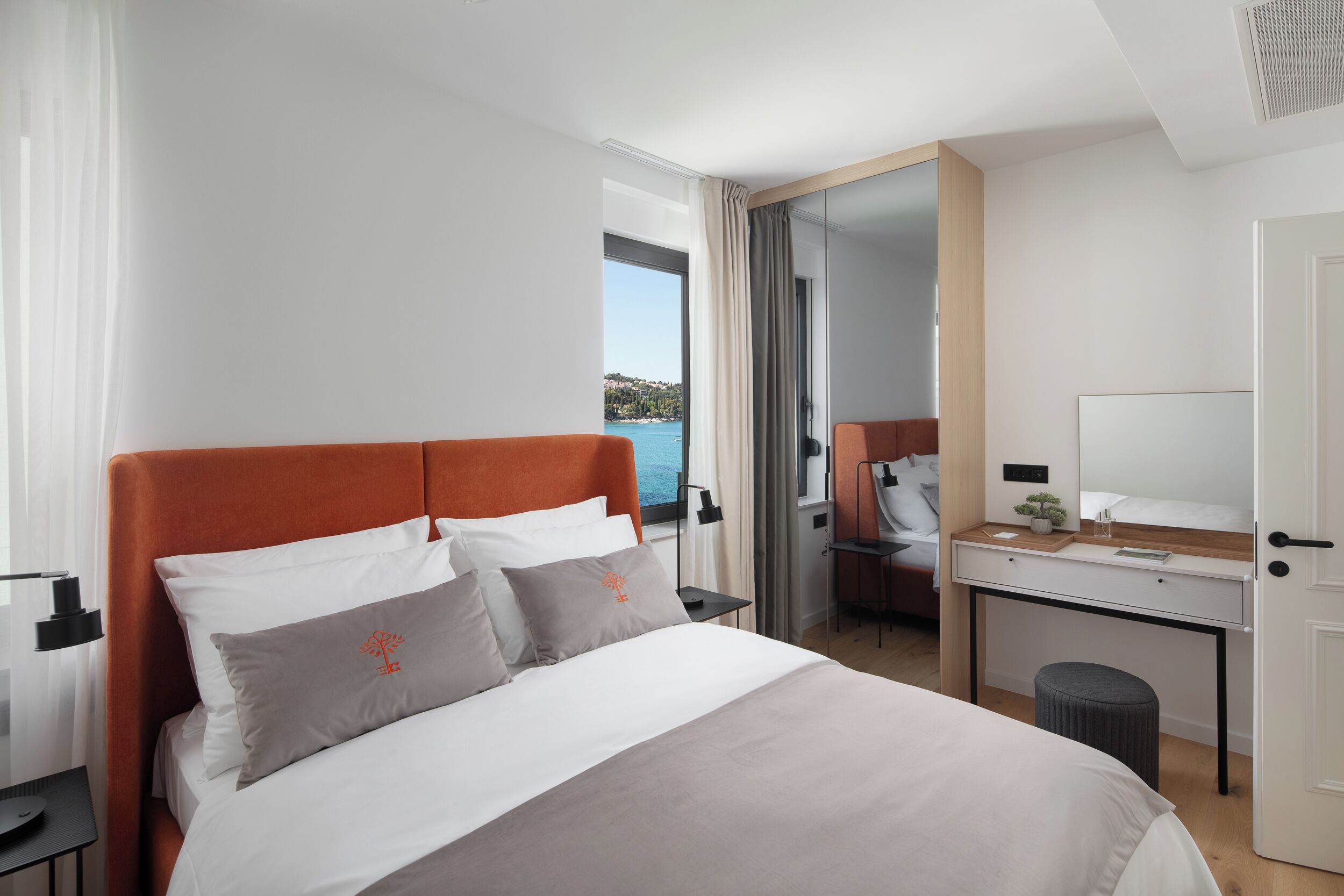Une chambre d’hôtel moderne dotée d’un grand lit, d’un bureau et offrant une vue sur la mer.