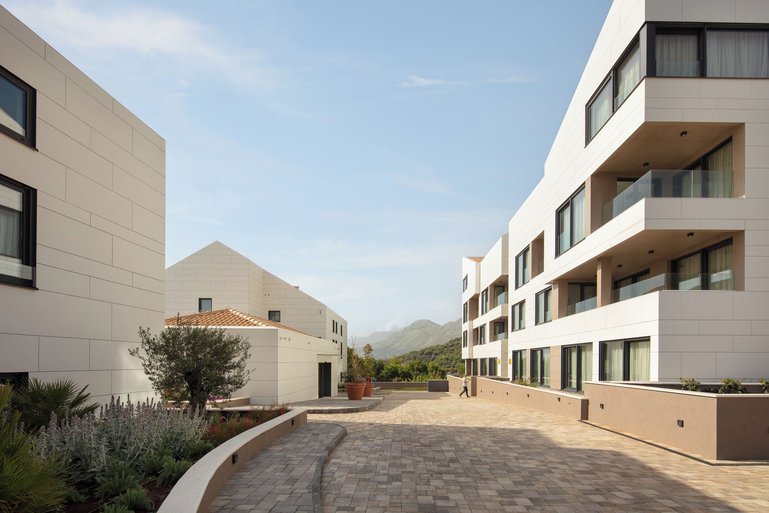 A modern building with a courtyard, featuring a mix of flat and sloped roofs, and a clear view of the surrounding landscape.