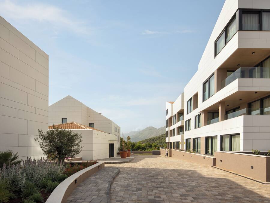 Un edificio moderno con un patio interior, que presenta una combinación de techos planos e inclinados, y una vista despejada del paisaje circundante.