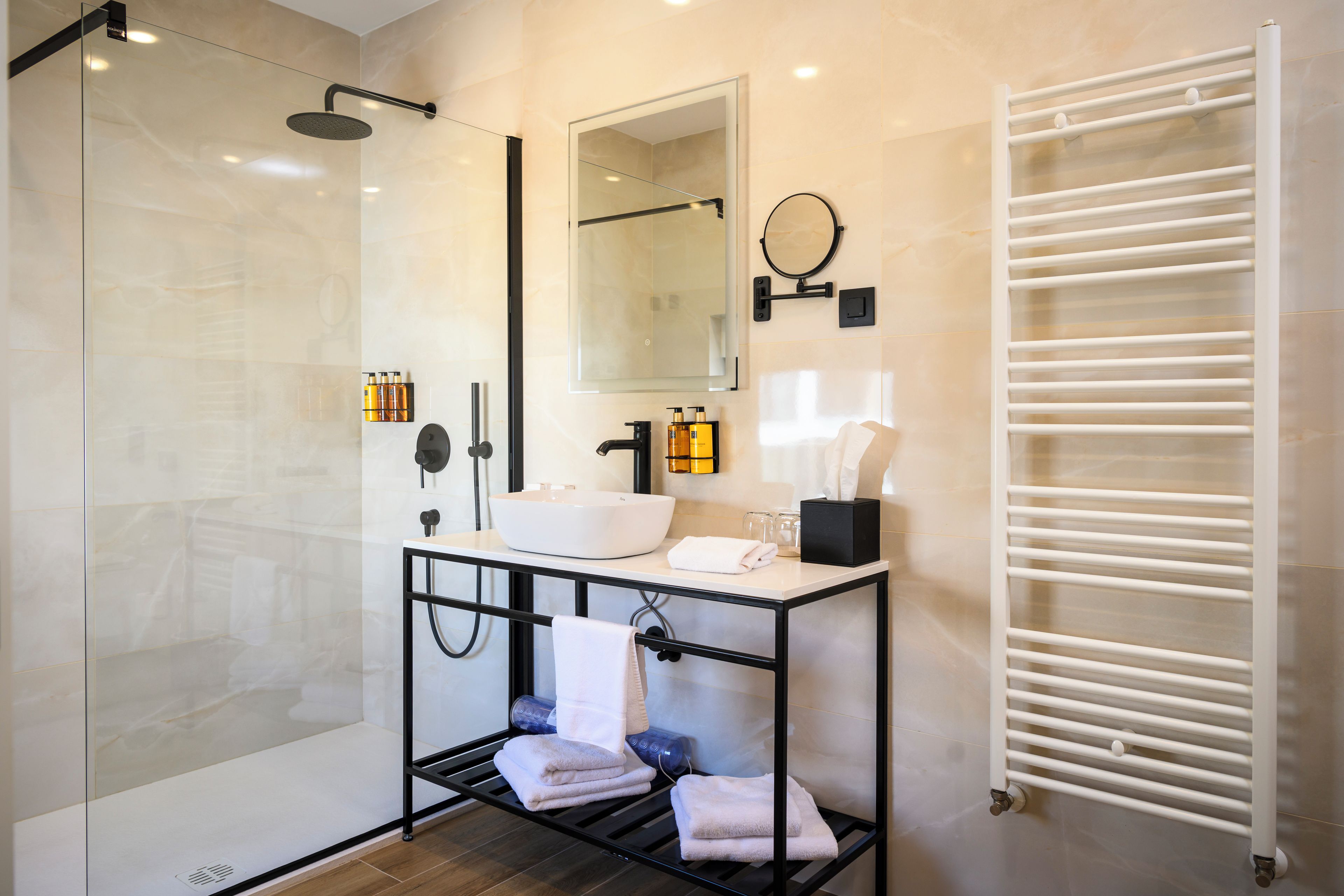 A modern bathroom with a glass shower enclosure, a white sink, a black vanity, and a towel rack.