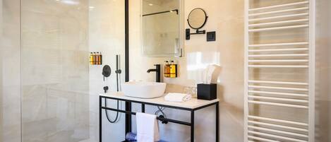 A modern bathroom with a glass shower enclosure, a white sink, a black vanity, and a towel rack.
