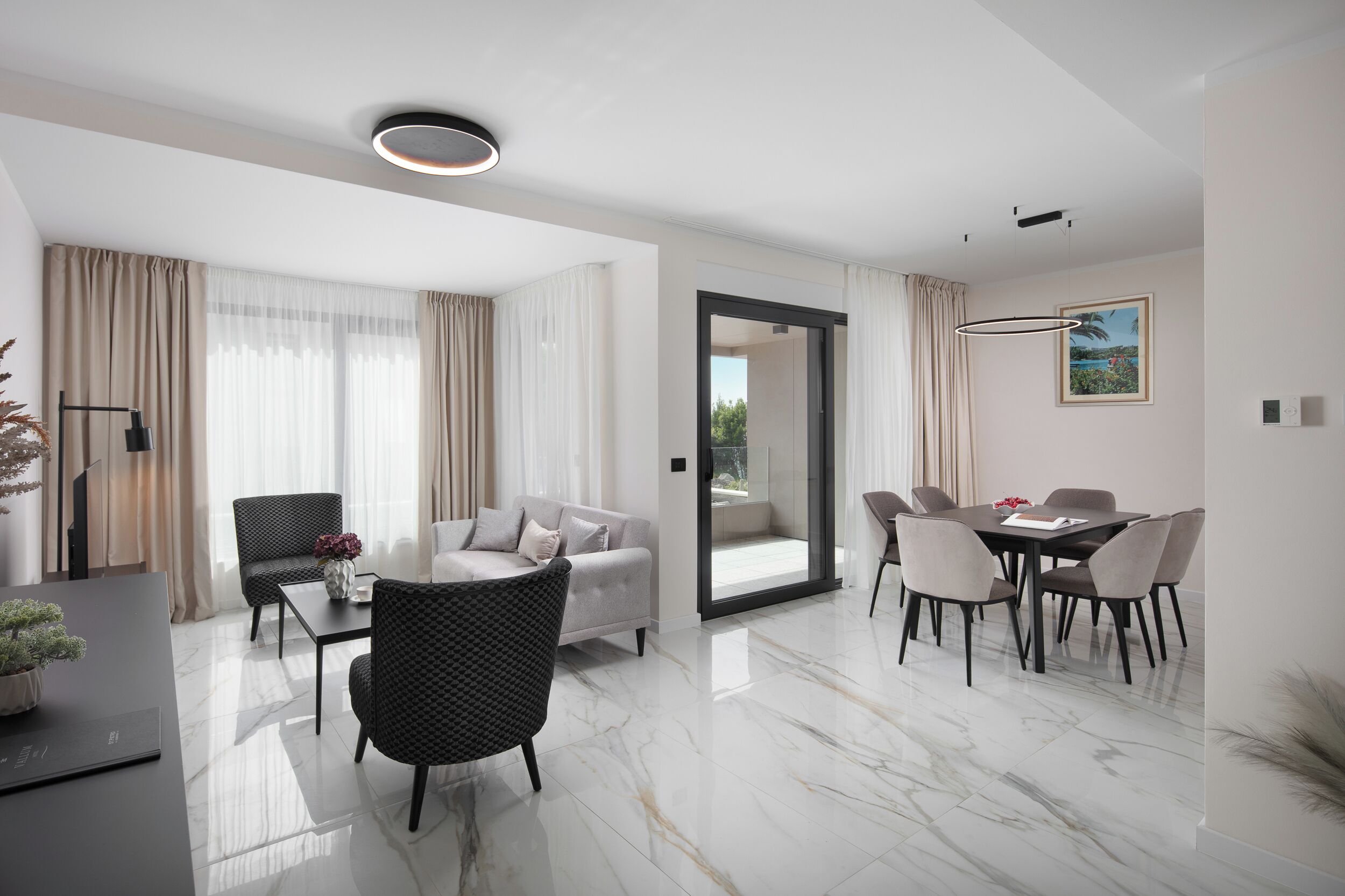 A modern living room with a sofa, chairs, a dining table, and a large window with curtains.