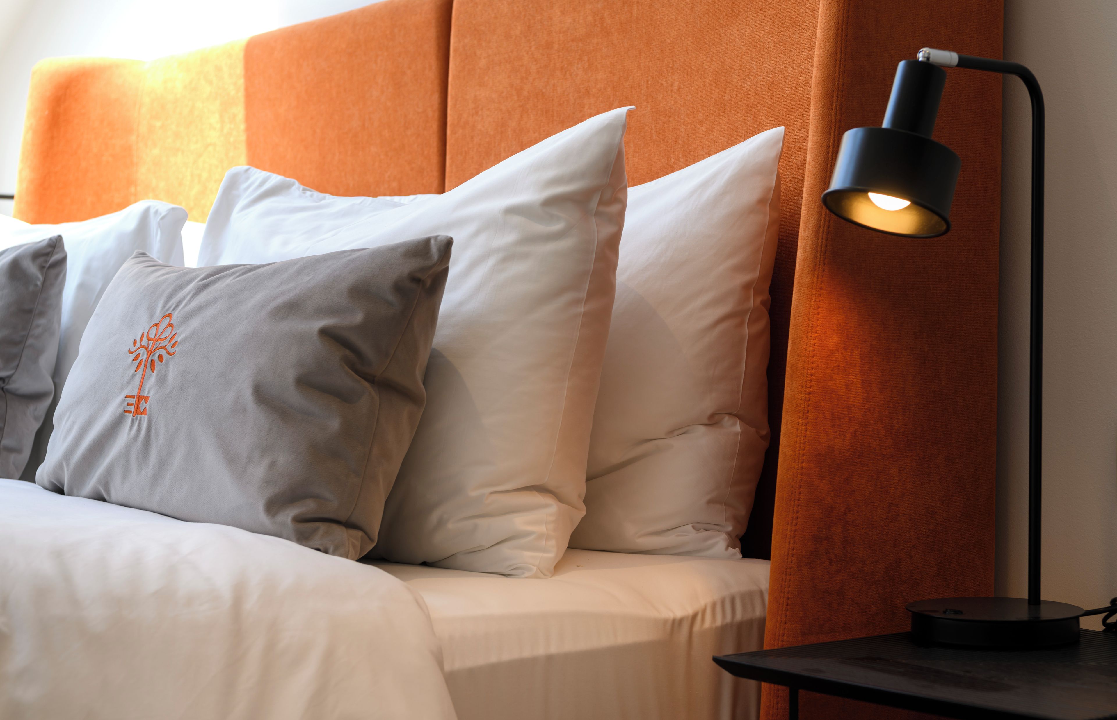Una cama con varias almohadas y una mesita de noche con lámpara.