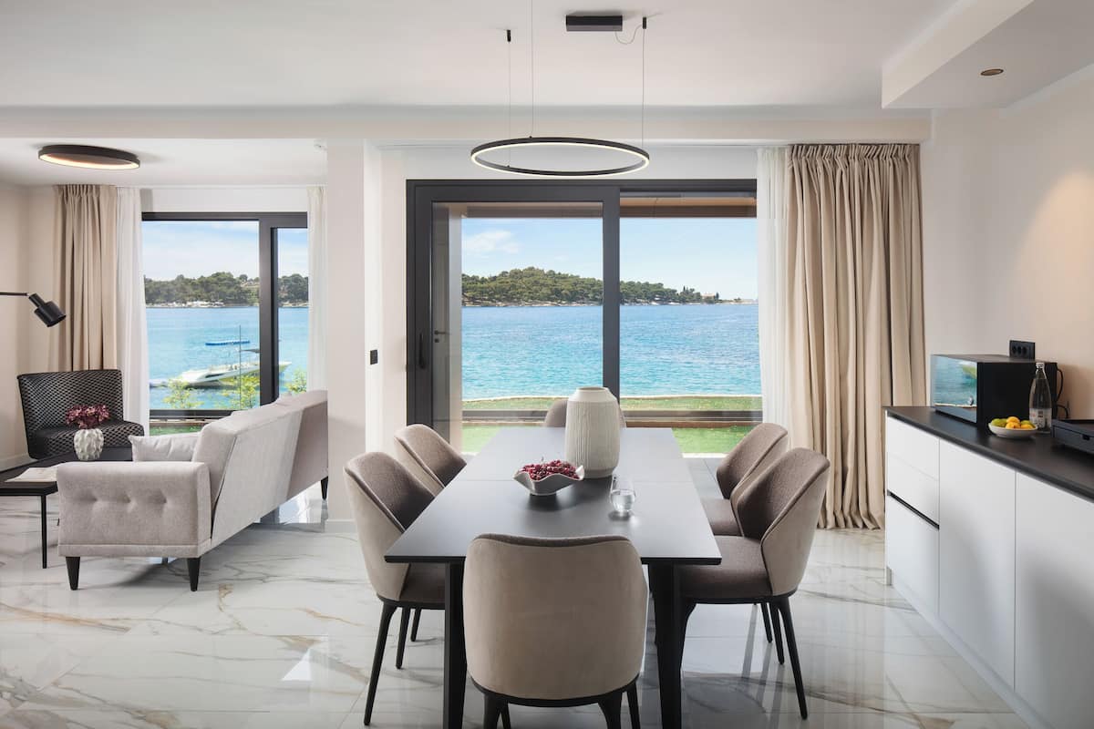 A modern dining area with a view of the sea, a sofa, and a table with chairs.