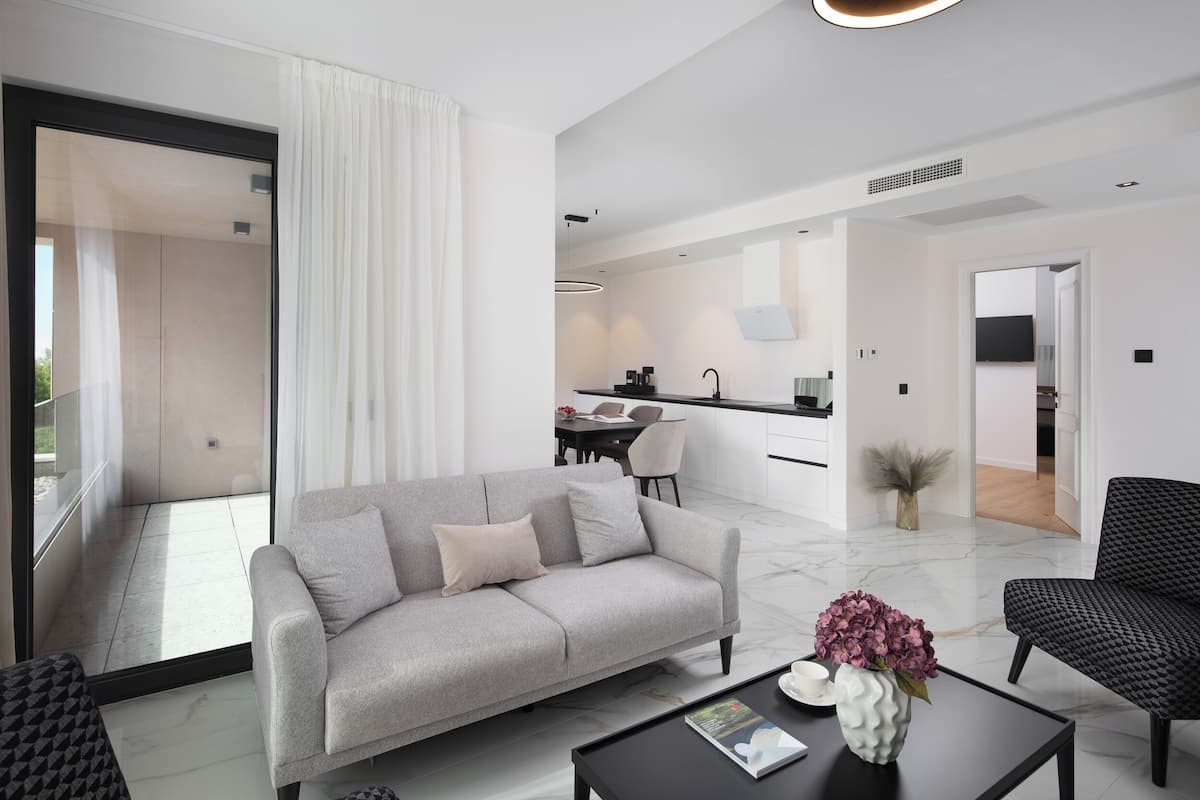 A modern living room with a grey sofa, a black coffee table, and a vase of flowers.