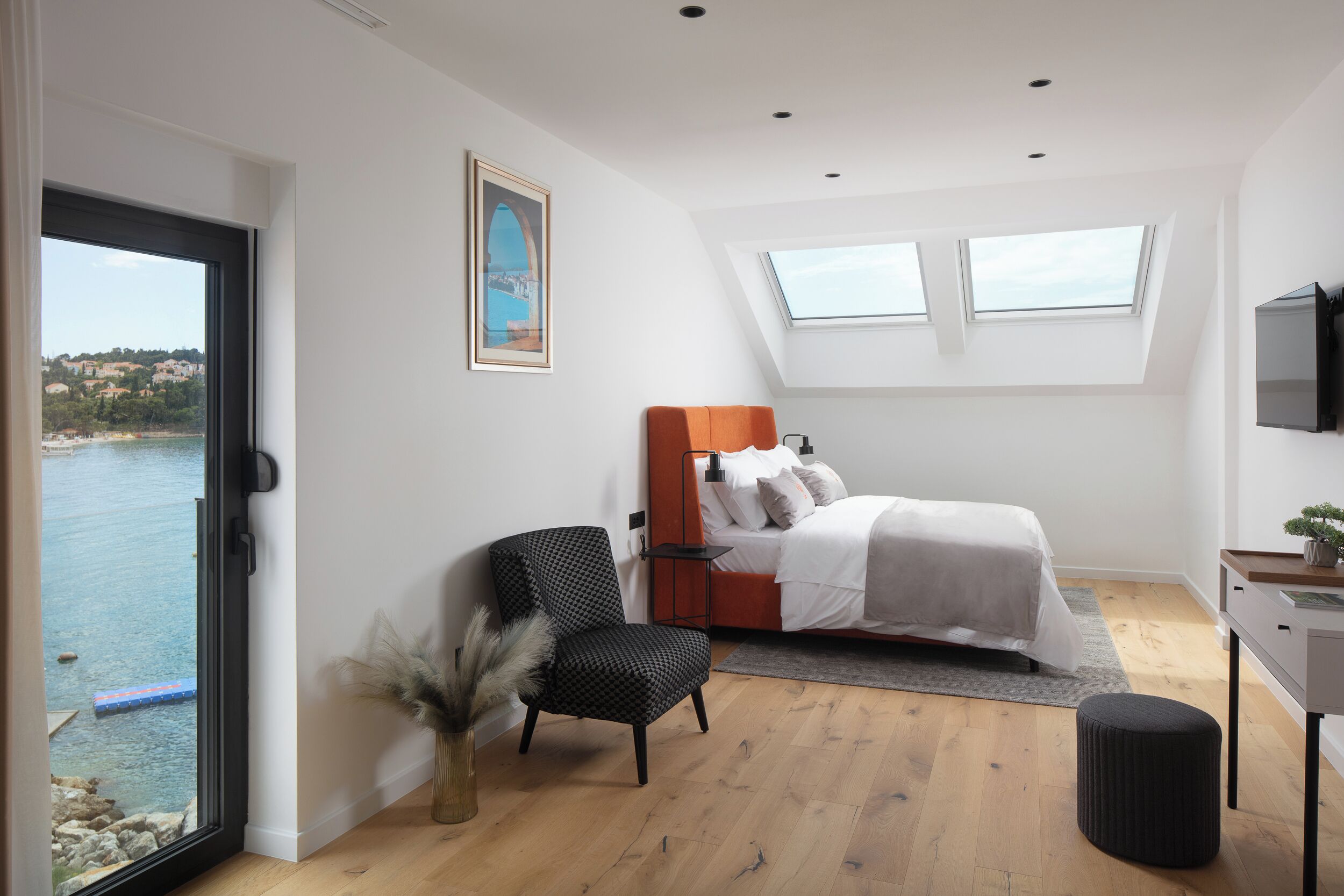 Un dormitorio con cama, una silla, un escritorio y vista al mar.