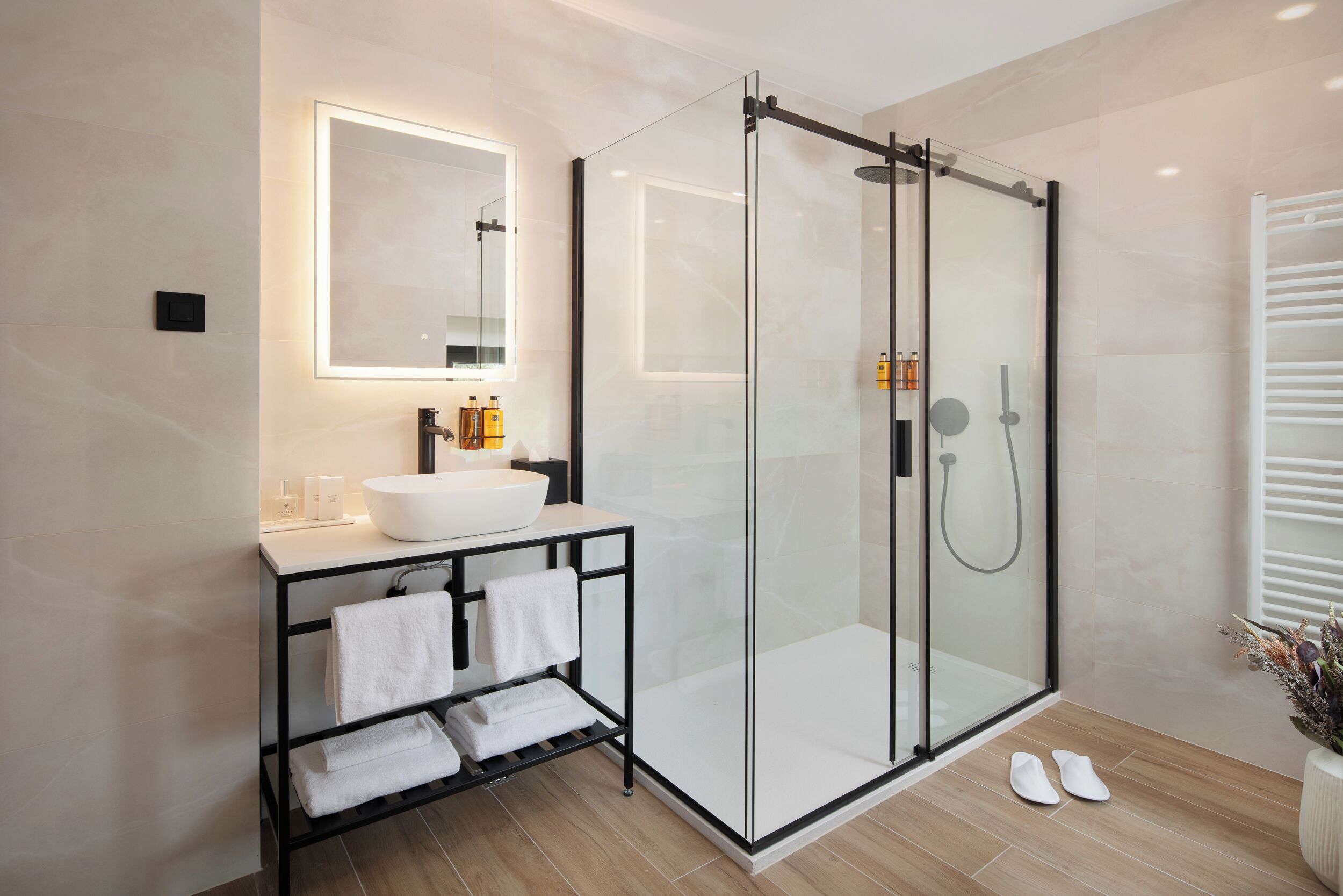 A modern bathroom with a glass-enclosed shower, a white sink, and a black vanity.