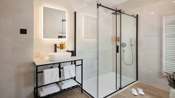 A modern bathroom with a glass-enclosed shower, a white sink, and a black vanity.