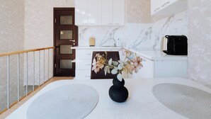 A modern kitchen with white cabinets, a marble backsplash, and a black toaster.