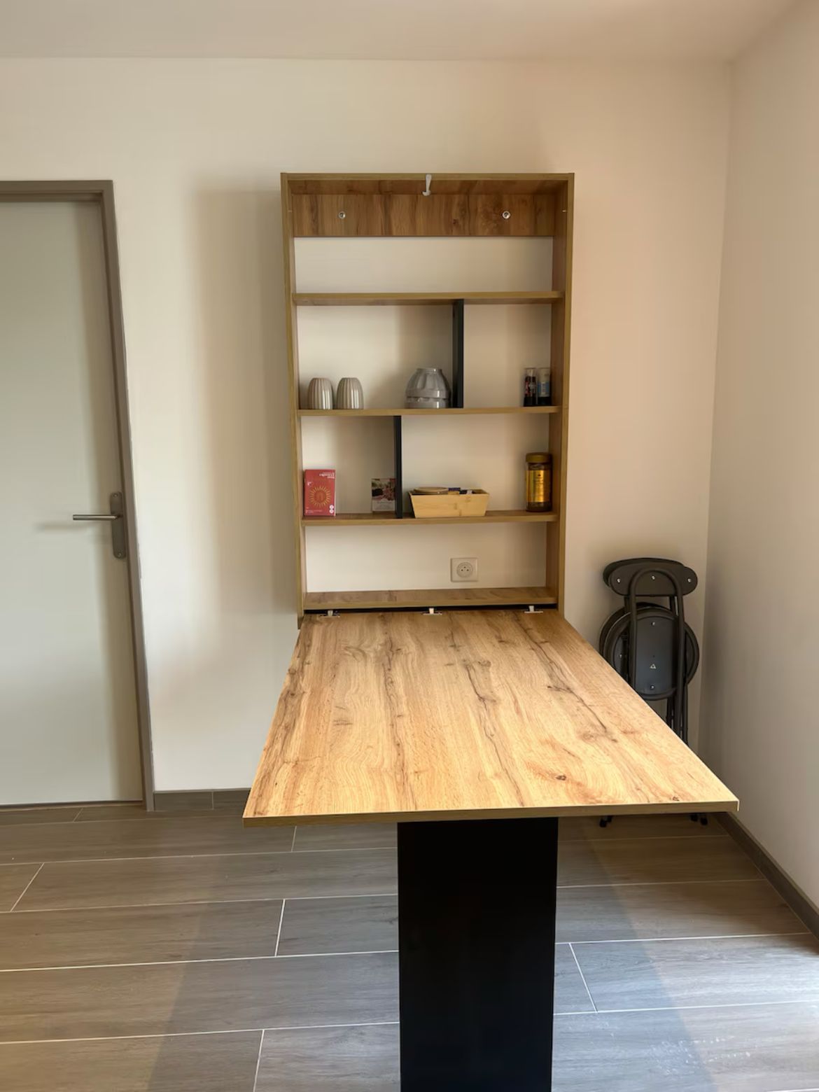Una habitación con una mesa de madera y una estantería empotrada en la pared.