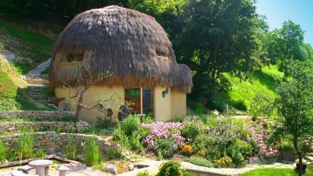 Una casa con techo de paja y un jardín delantero.
