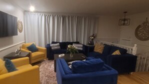 A living room with a sofa set, a coffee table, and a TV mounted on the wall.