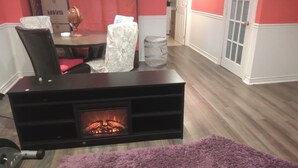 A cozy living room with a fireplace, a dining area with a table and chairs, and a hallway leading to another room.