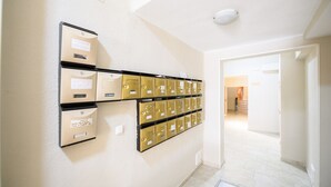 A hallway with a row of gold-colored mailboxes on the wall.