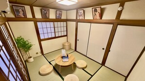 Perinteinen japanilainen huone, jossa on tatamimatto, matala pöytä tyynyineen ja liukuvat ovet.