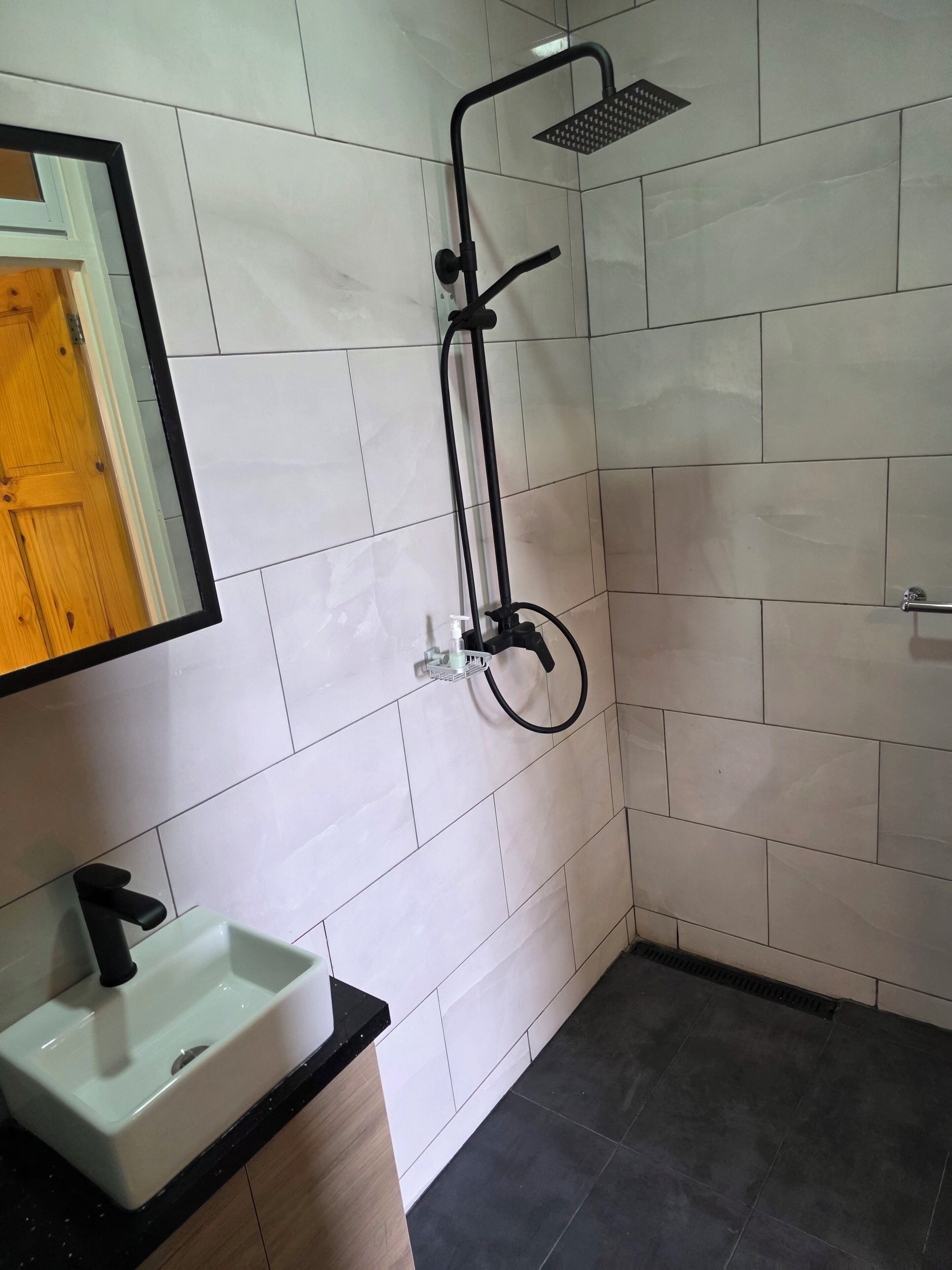 A bathroom with a shower, a sink, and a mirror.