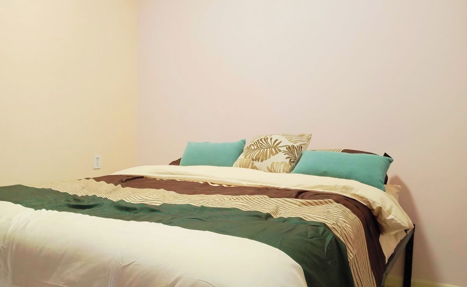 A single bed with a patterned bedspread, two pillows, and a bedside table.